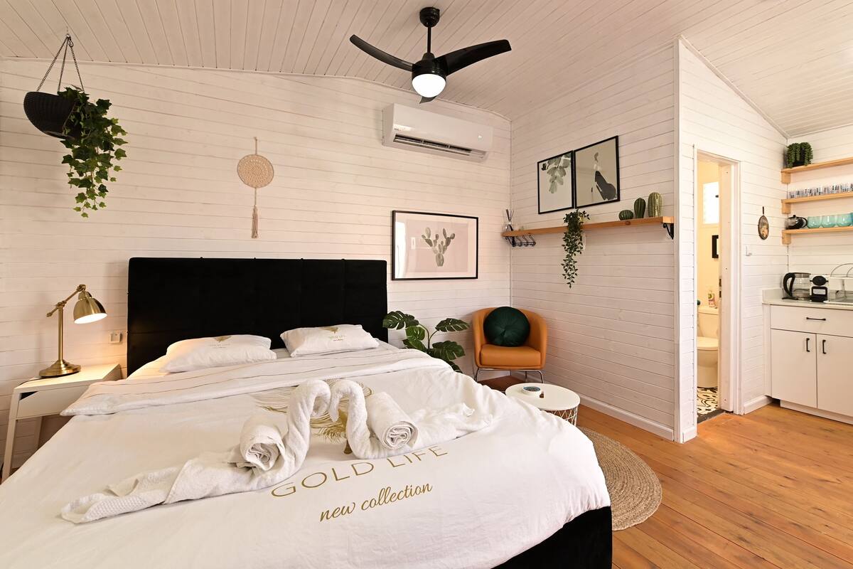 A hotel room with a bed, bedside table, lamp, and a ceiling fan.