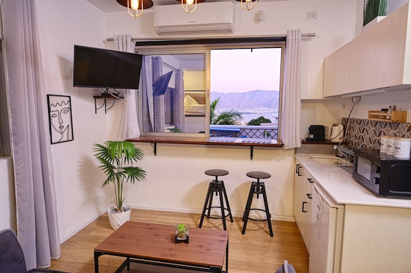 Un espace de vie compact comprenant une cuisine, un coin repas et une fenêtre donnant sur un paysage agréable.