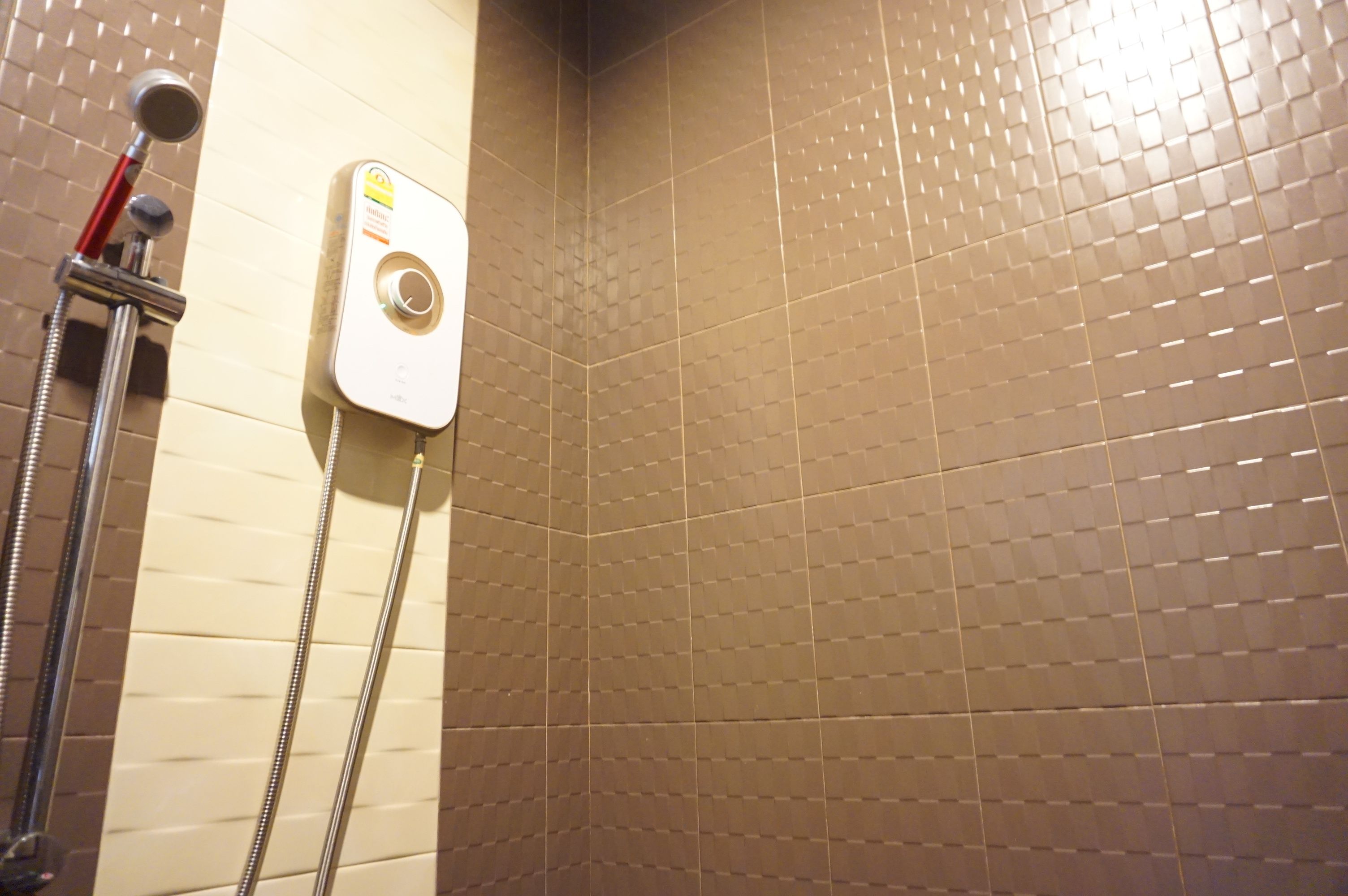 A bathroom with a shower, a handheld showerhead, and a wall-mounted control panel.
