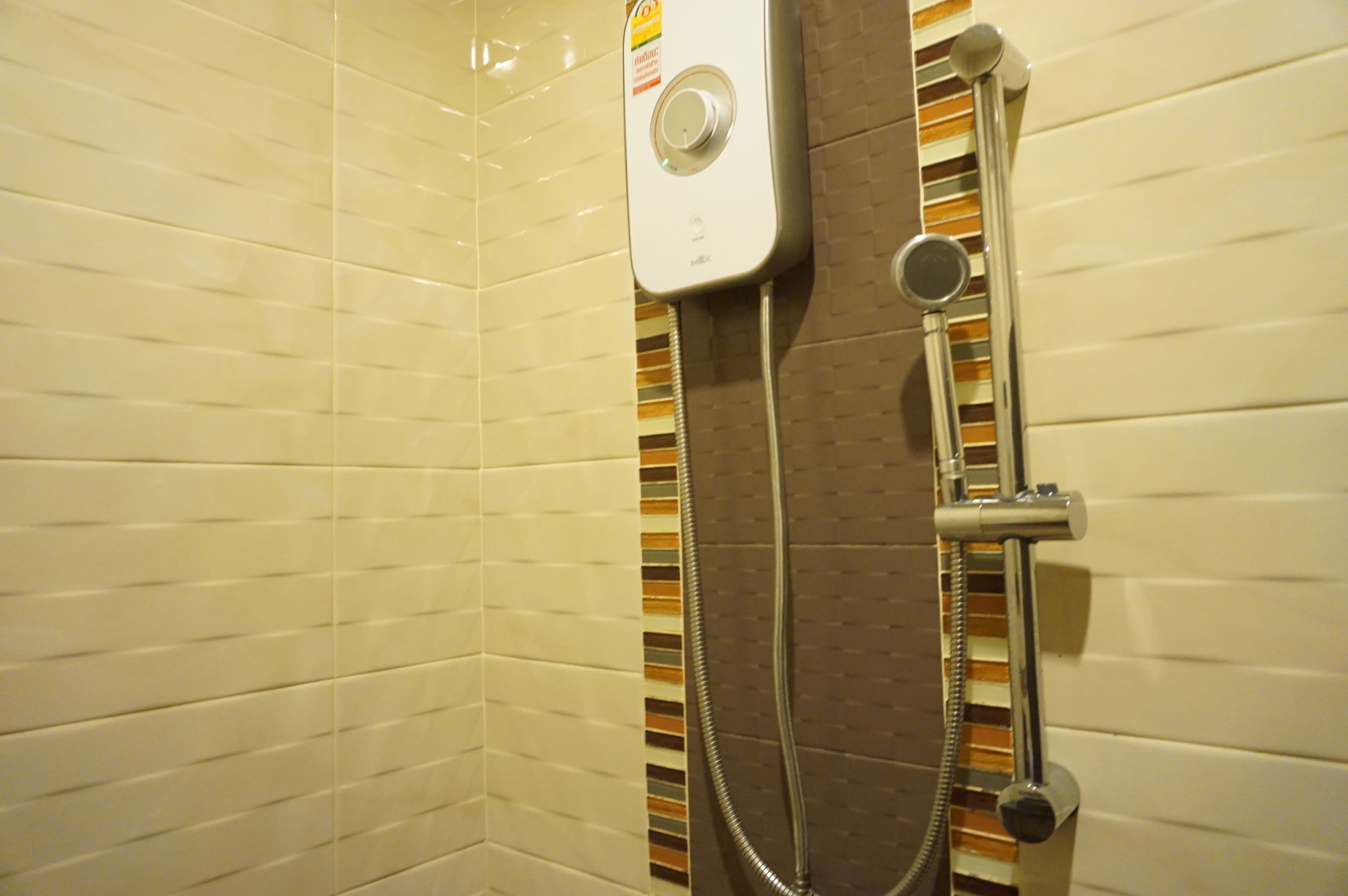 Een douche met een handdouche en een bedieningspaneel aan de wand.