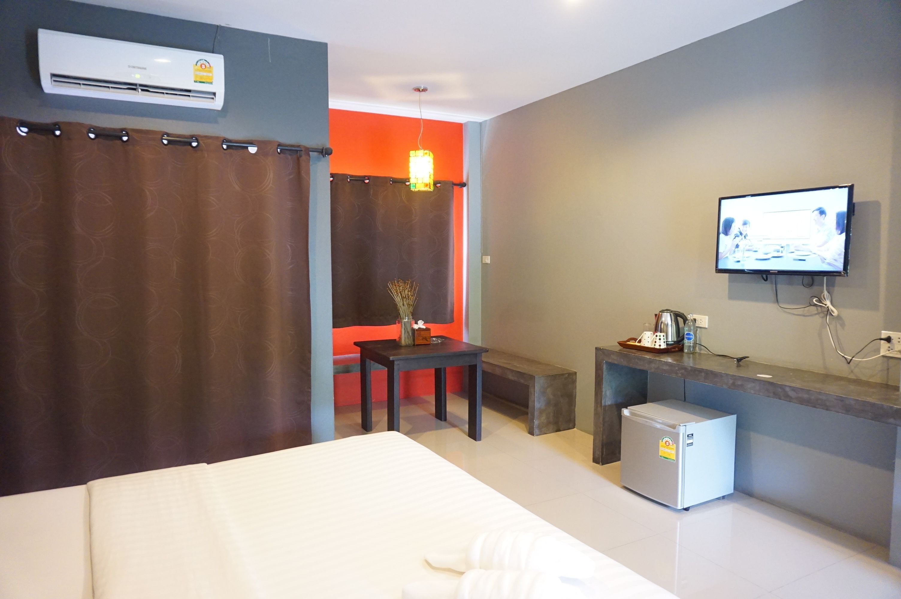 Habitación de hotel con cama, una mesita, televisión y un mini refrigerador.