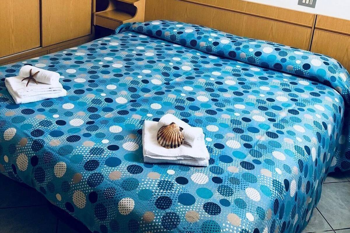 Quarto de hotel com uma cama, guarda-roupa de madeira e três quadros na parede.
