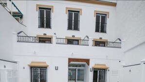 A multi-story building with balconies, a covered outdoor seating area, and a glass entrance. - Hostal Boutique Bajamar (Nerja)