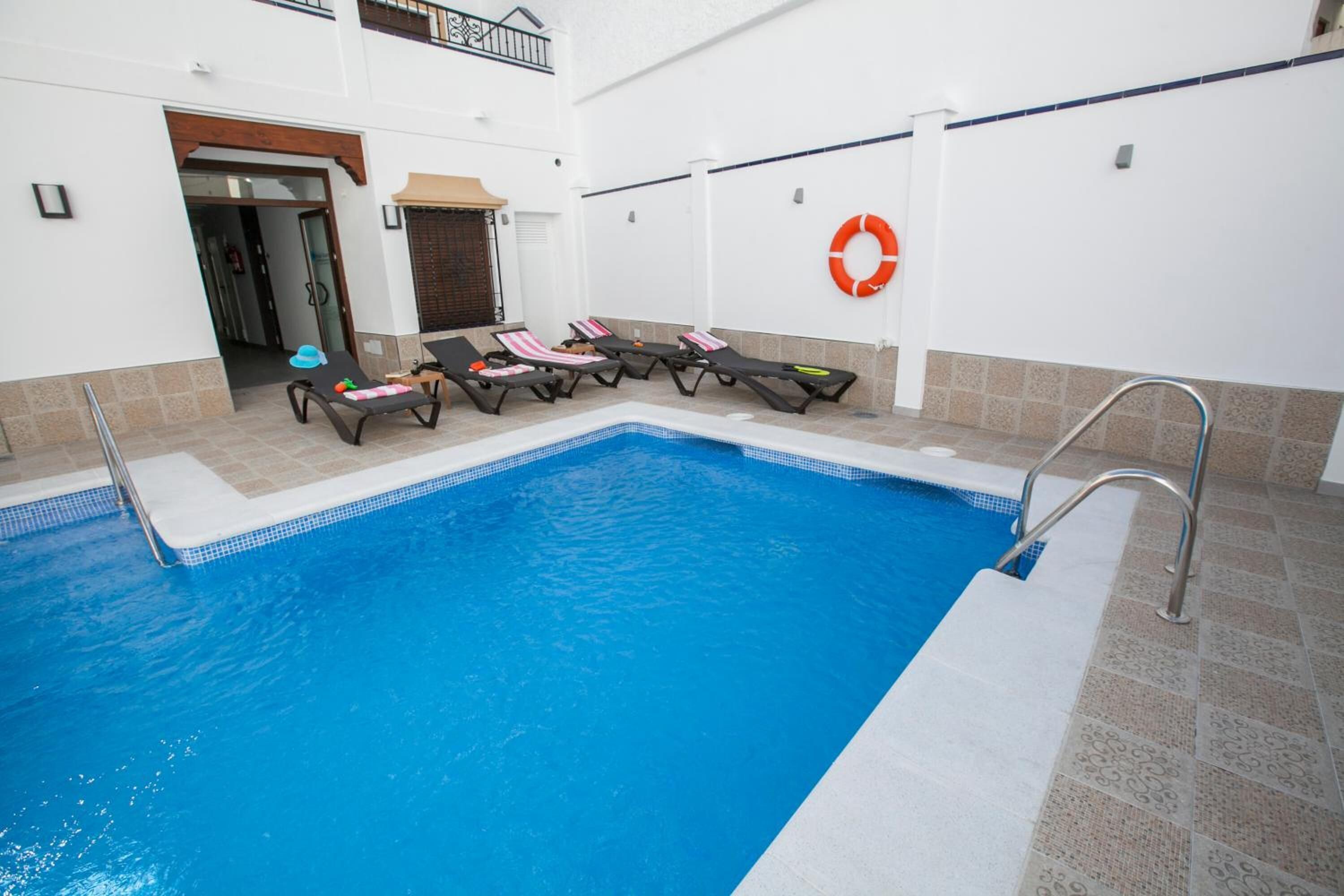 A swimming pool with lounge chairs and a lifebuoy on the wall.
