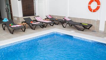 Un espace piscine avec des chaises longues et une bouée de sauvetage fixée au mur.