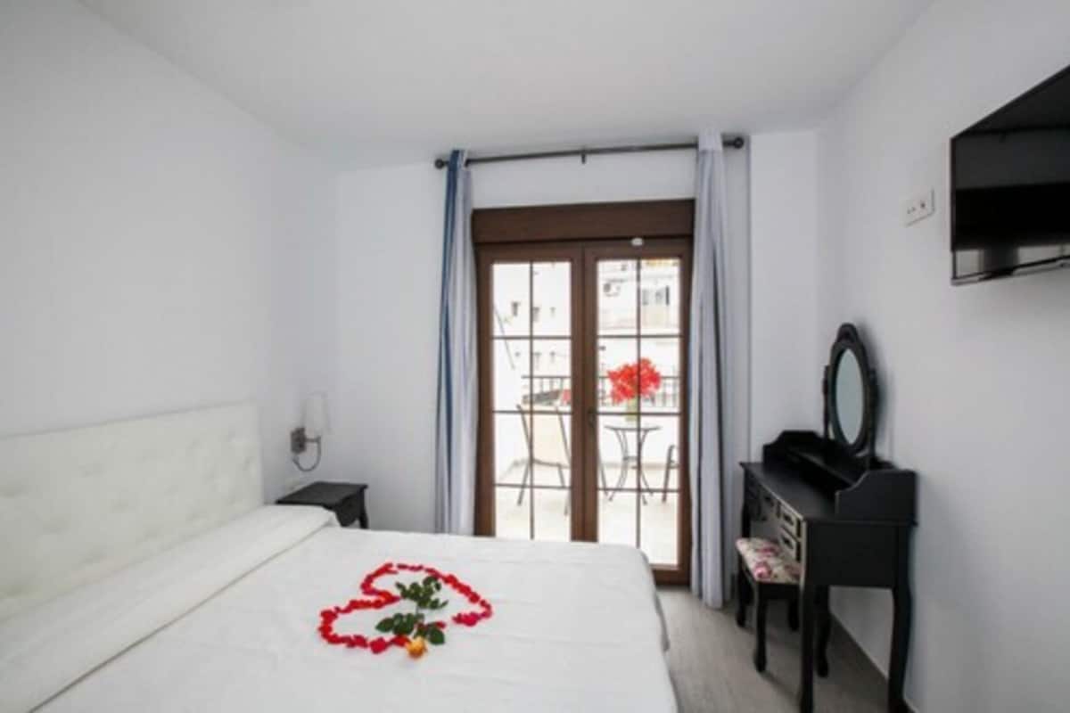 Habitación de hotel con cama, piano, escritorio y vistas al exterior.