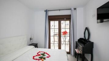 Habitación de hotel con cama, piano, escritorio y vistas al exterior.