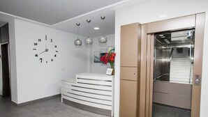 A reception area with a wall clock, a white counter, and an elevator. - Hostal Boutique Bajamar (Nerja)