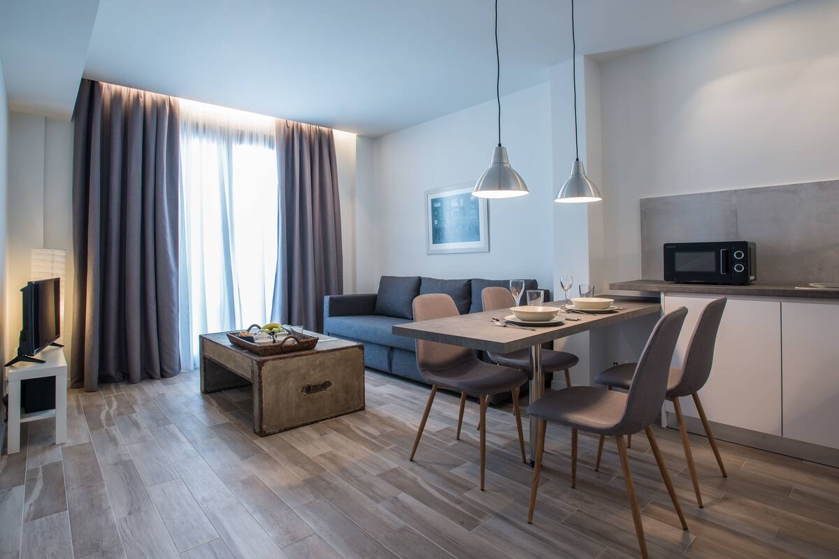 A modern living space with a dining area, kitchen, and seating area.
