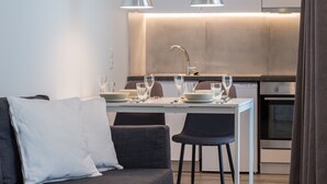 A modern kitchen with a dining area, including a table set for two with glasses and plates. - Spot Apart (Athens)