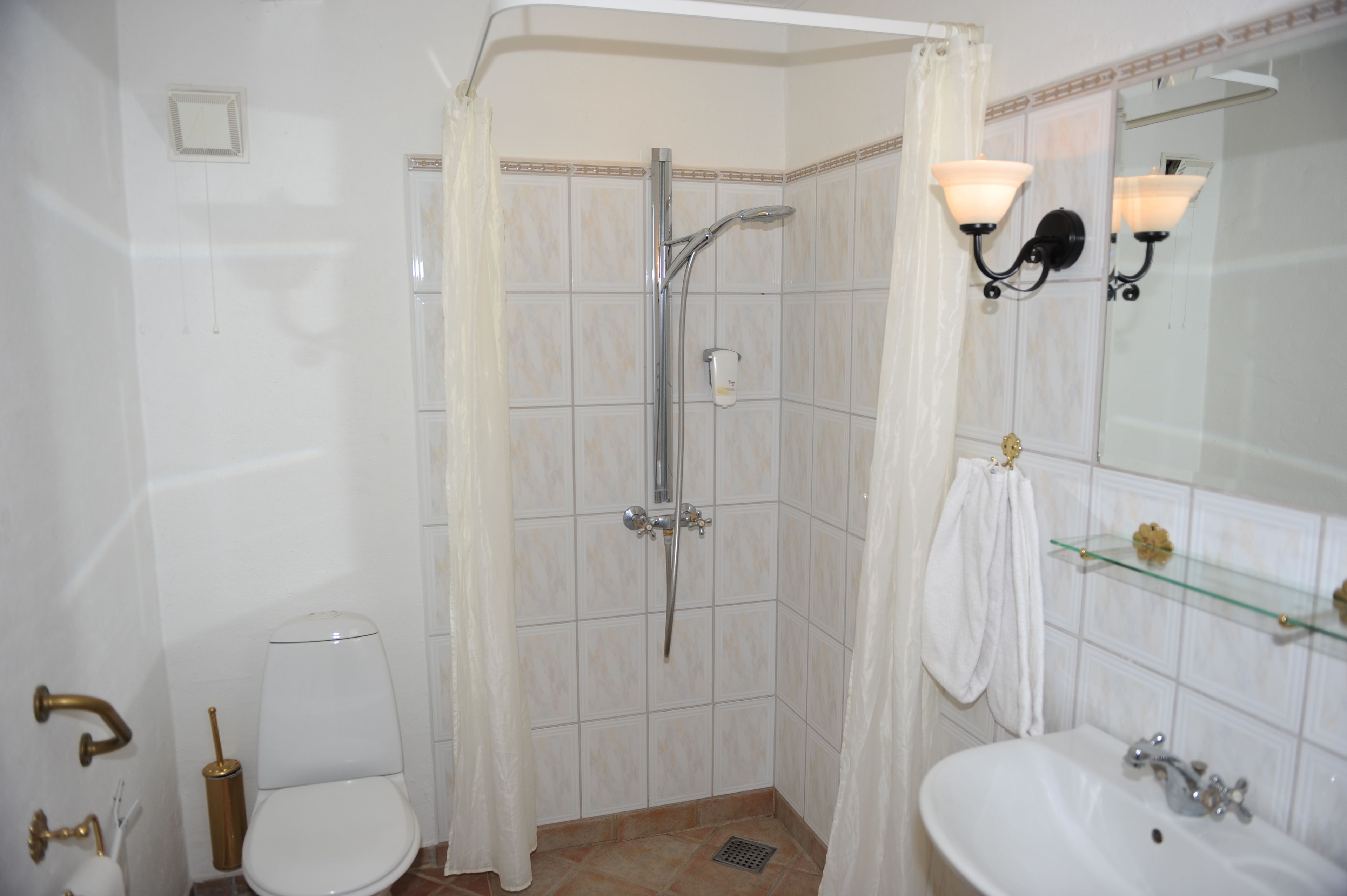 A bathroom with a shower, toilet, sink, and mirror.