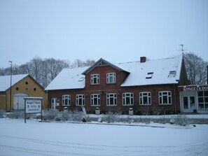 A two-story building with a snow-covered roof and a sign indicating it is a hotel and restaurant.