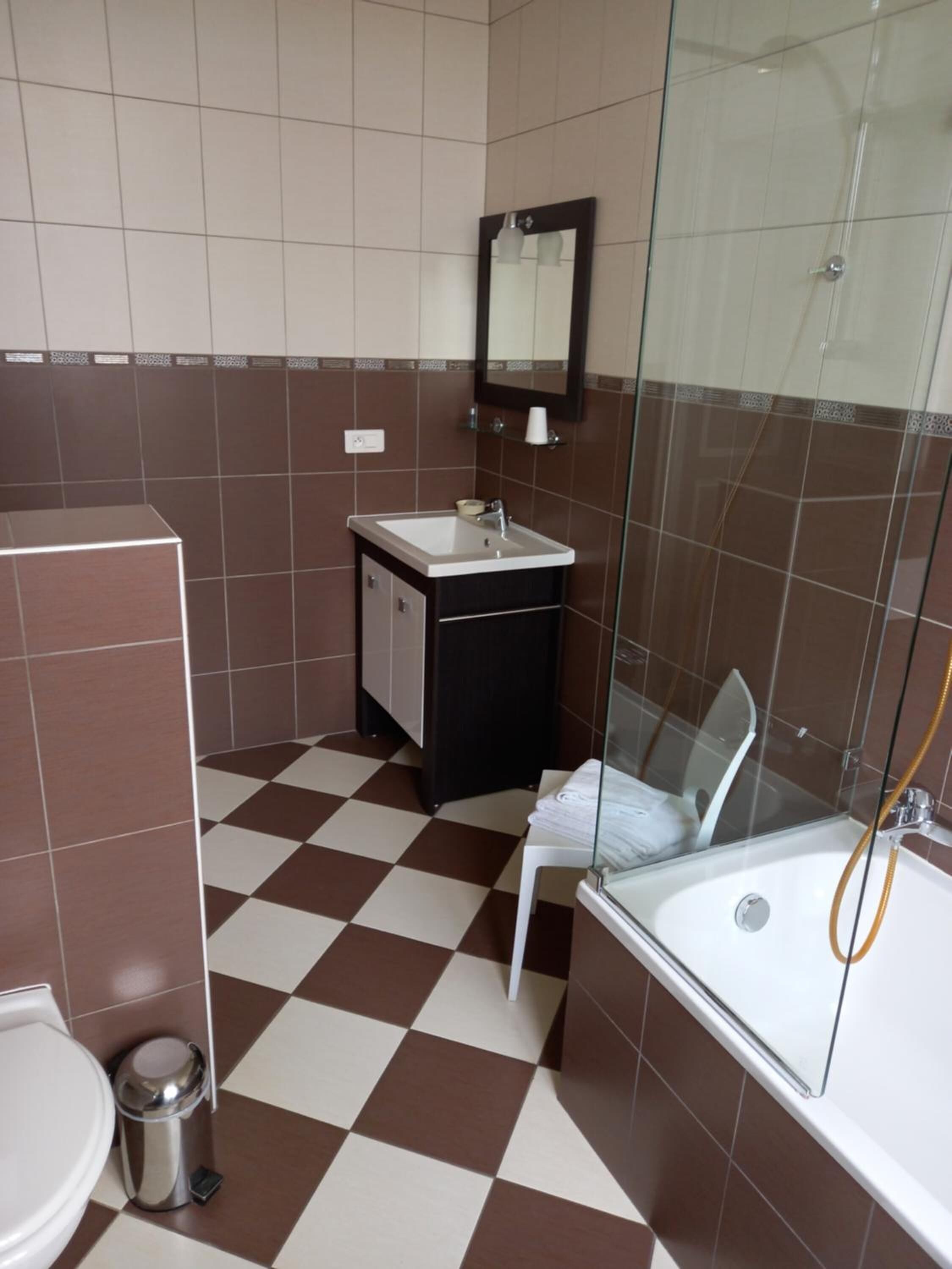 Un bagno con pavimento a scacchi, un lavandino, uno specchio, un WC e una zona doccia.