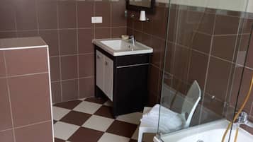 Un bagno con pavimento a scacchi, un lavandino, uno specchio, un WC e una zona doccia.
