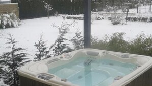 Banyera d'hidromassatge amb terrassa de fusta i zona de porxo coberta.