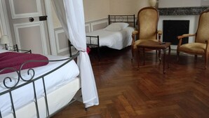 Una habitació amb un llit, dues cadires, una llar de foc i un mirall a la paret.