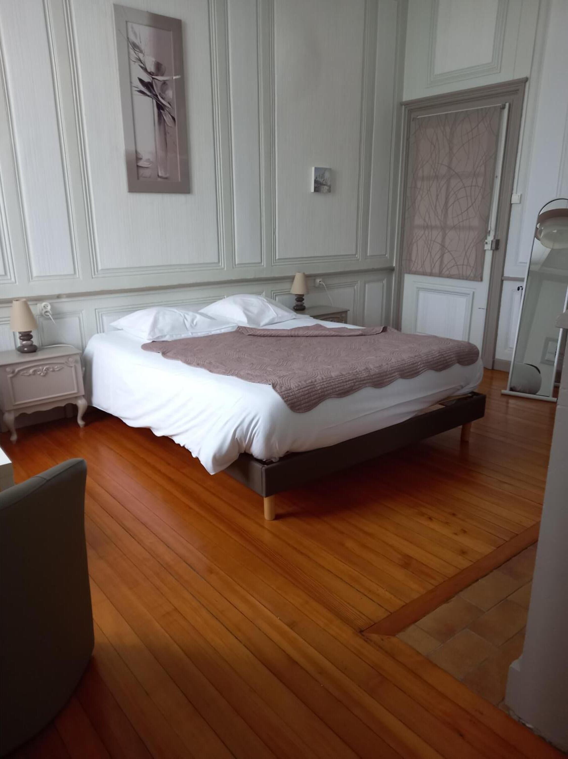 A neatly arranged bedroom with a bed, bedside tables, and a mirror.