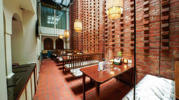 A restaurant with brick walls, wooden furniture, and hanging lights. - Woodapple Residency (New Delhi)