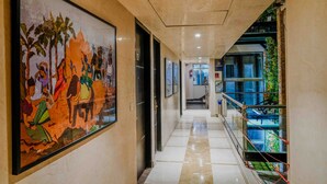 A hotel corridor with a large mural, a glass railing, and a staircase leading to an upper level. - Woodapple Residency (New Delhi)
