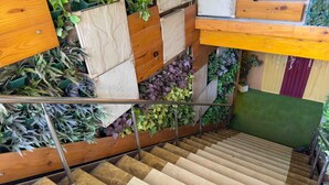 A staircase with wooden steps and a metal handrail, surrounded by various plants and greenery. - Woodapple Residency (New Delhi)