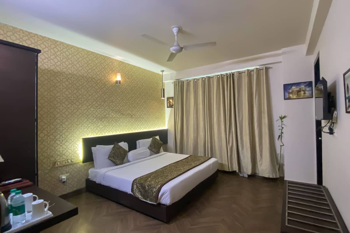 A hotel room with a bed, a ceiling fan, a nightstand, and a window with curtains.