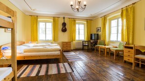 A room with a bunk bed, a desk with a chair, a television, and a violin hanging on the wall. - Pension Gardena Kaplická 21 (Cesky Krumlov)