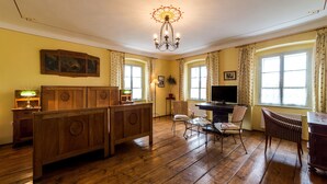 A room with a wooden bench, a television, and a chandelier. - Pension Gardena Kaplická 21 (Cesky Krumlov)