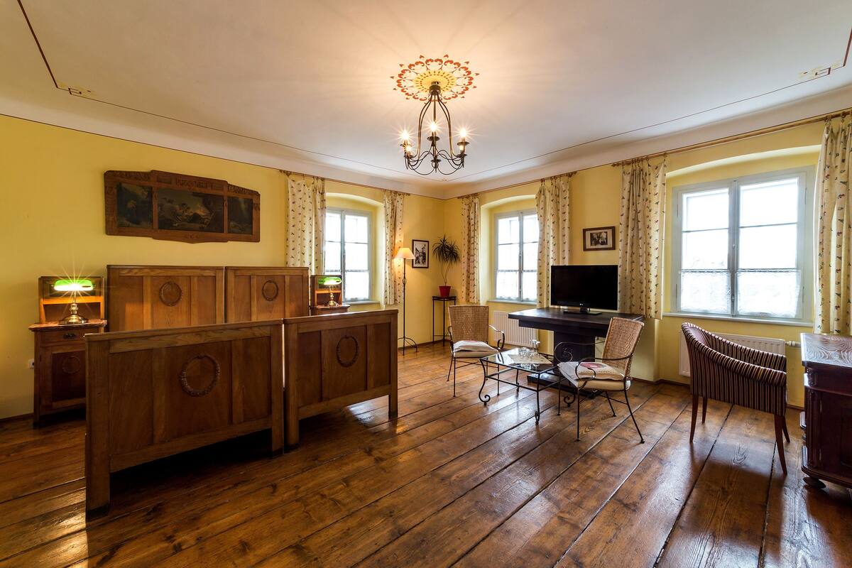 A room with a wooden bench, a television, and a chandelier.