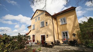 A two-story building with a sign reading "Pension Garten." It features a stone-paved courtyard with outdoor seating and potted plants. - Pension Gardena Kaplická 21 (Cesky Krumlov)