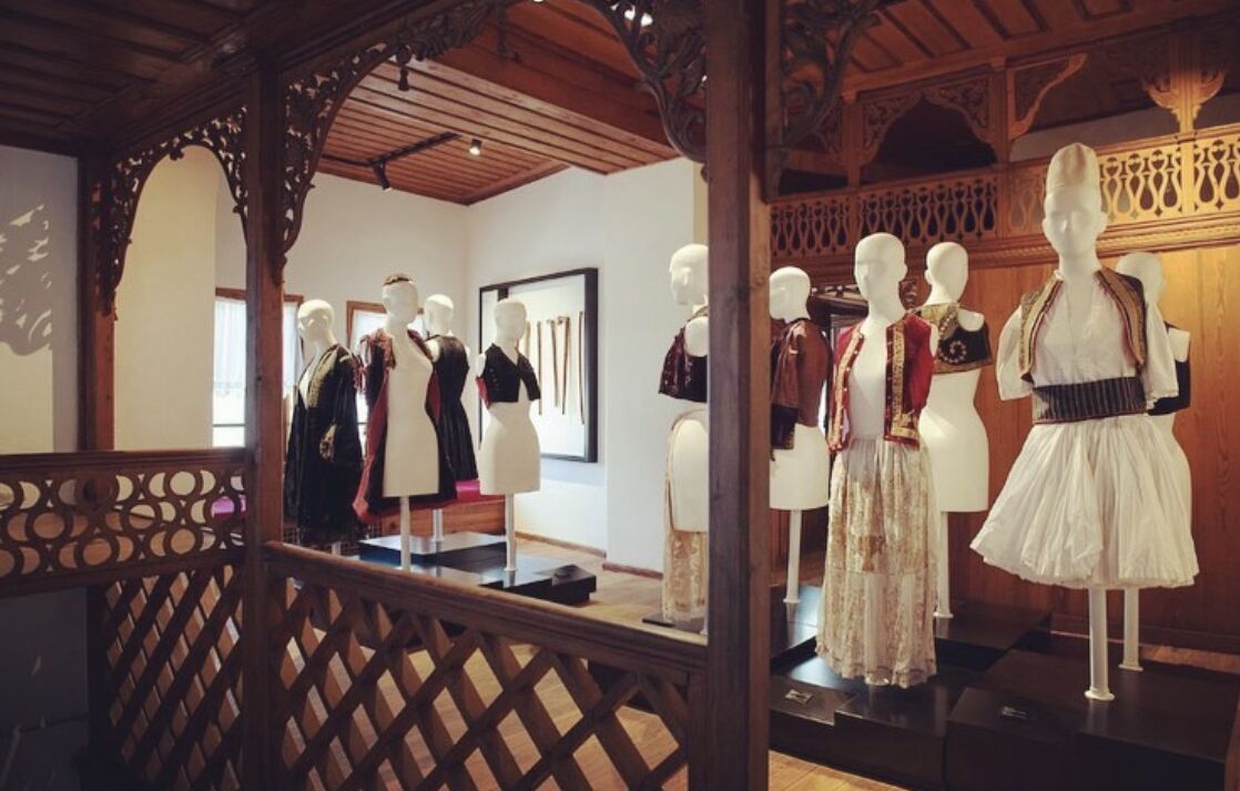 A room with wooden beams and a lattice railing, displaying mannequins dressed in traditional attire.
