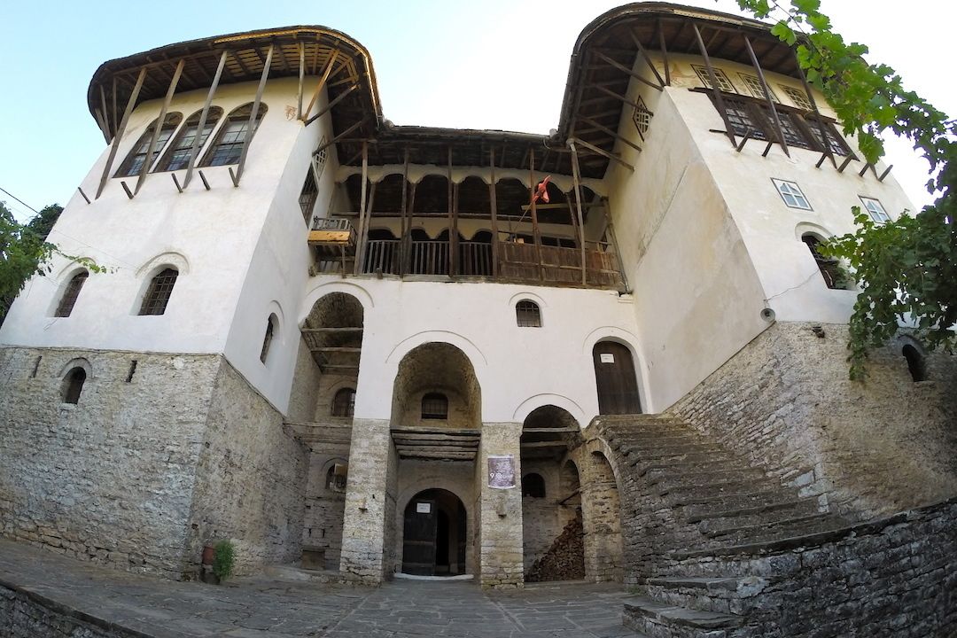 A historic building with a central archway, multiple balconies, and a stone base.