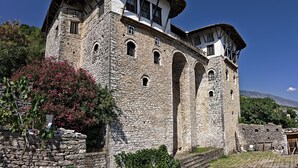 Ein historisches Steinhaus mit mehreren Bögen und einem steilen Satteldach.