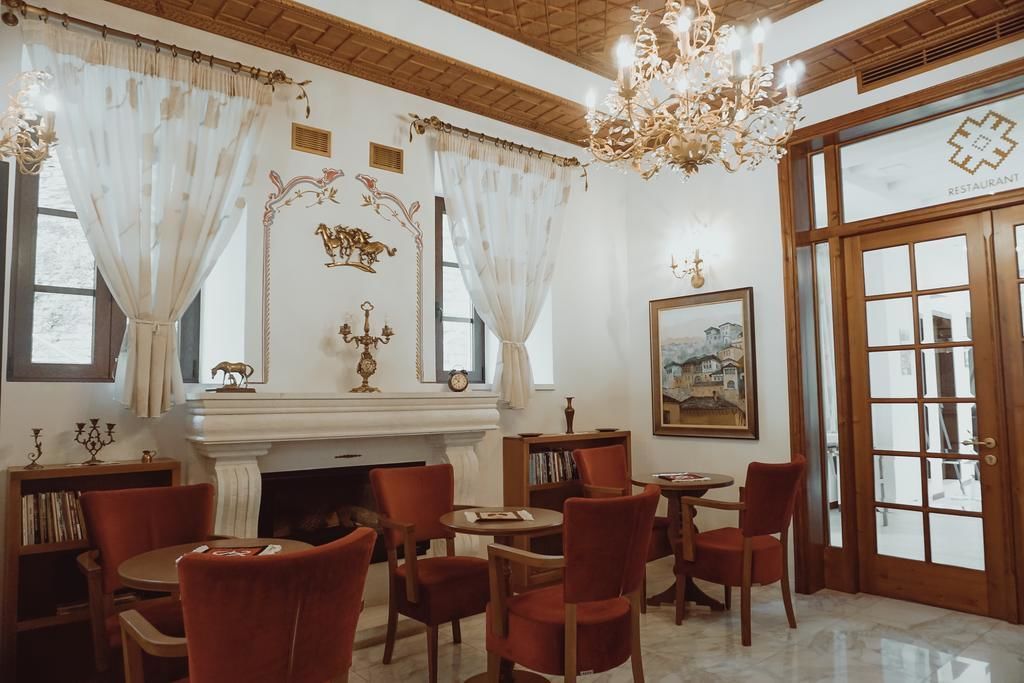A dining area with red chairs, a fireplace, and a chandelier.
