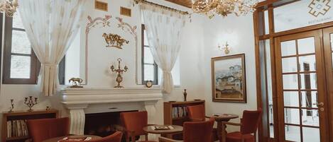 A dining area with red chairs, a fireplace, and a chandelier.