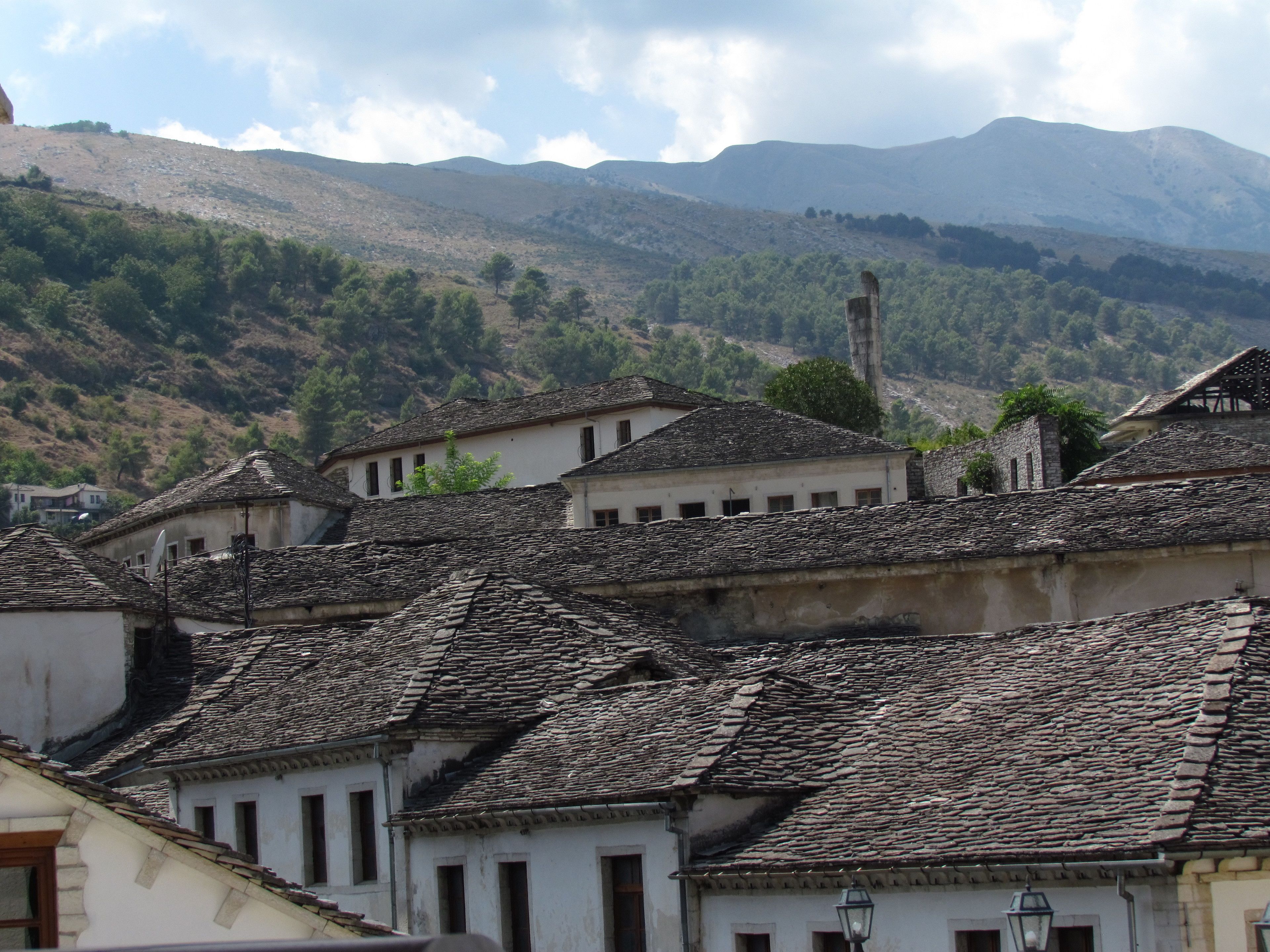 Un conjunto de edificios tradicionales con tejados de piedra, frente a colinas y una montaña.