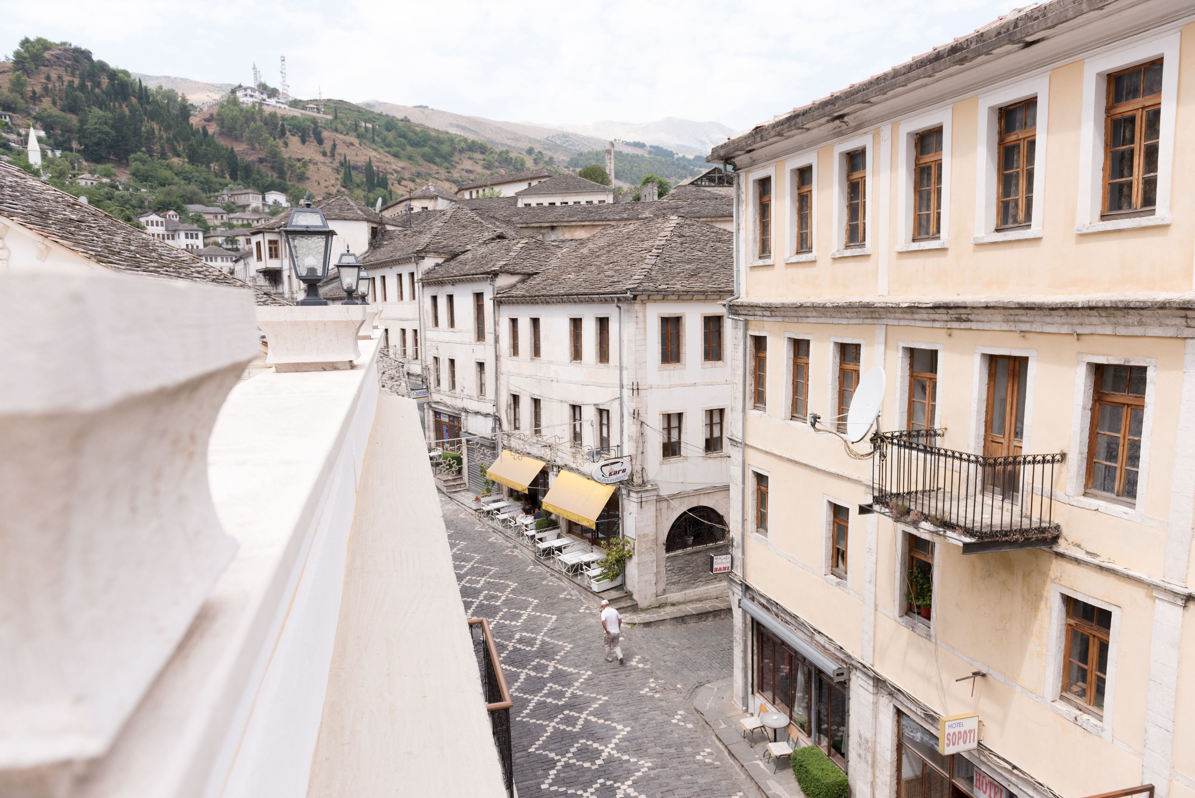 A street view of a traditional town with buildings featuring balconies and a cobblestone street.