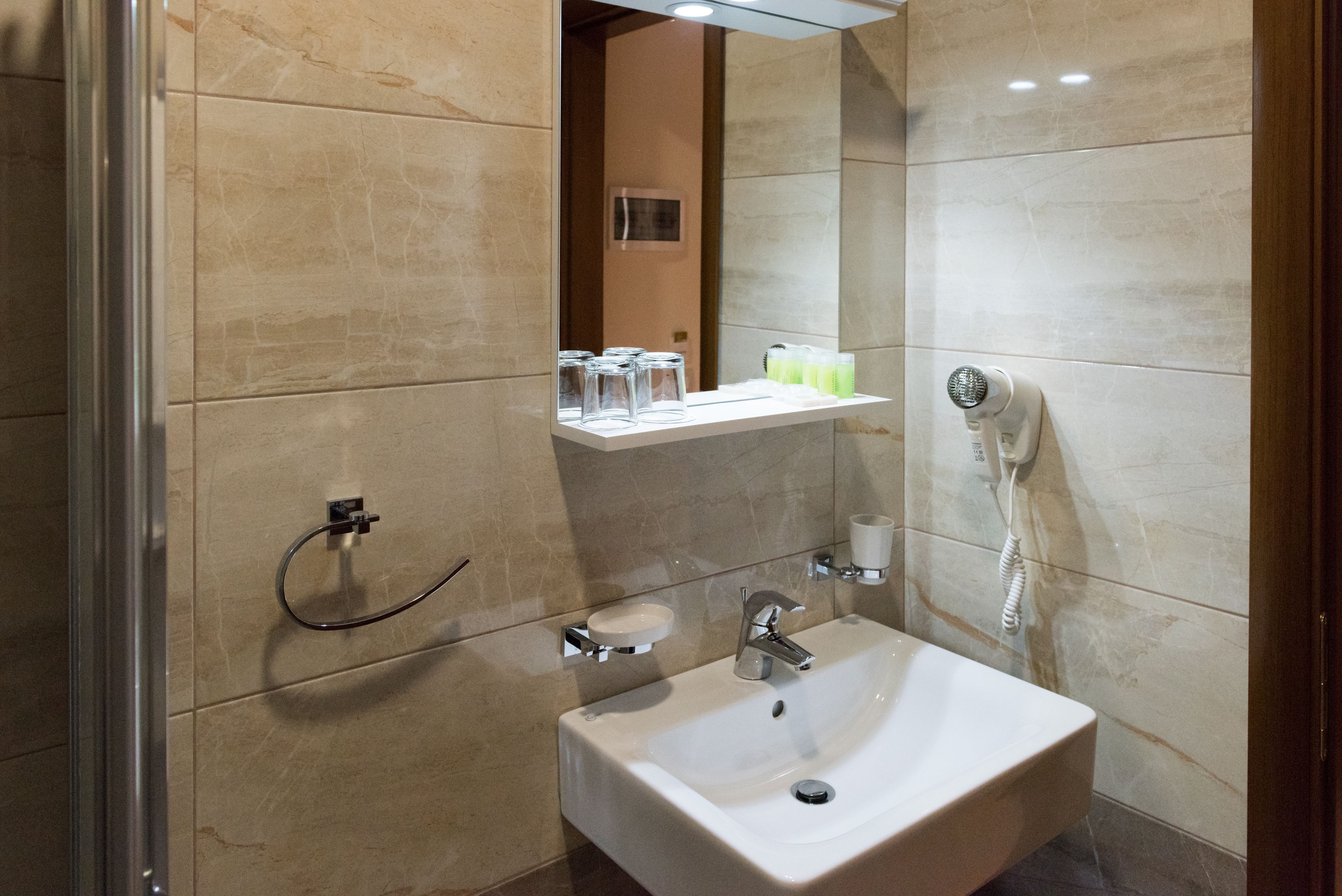 A modern bathroom with a sink, mirror, and towel rack.