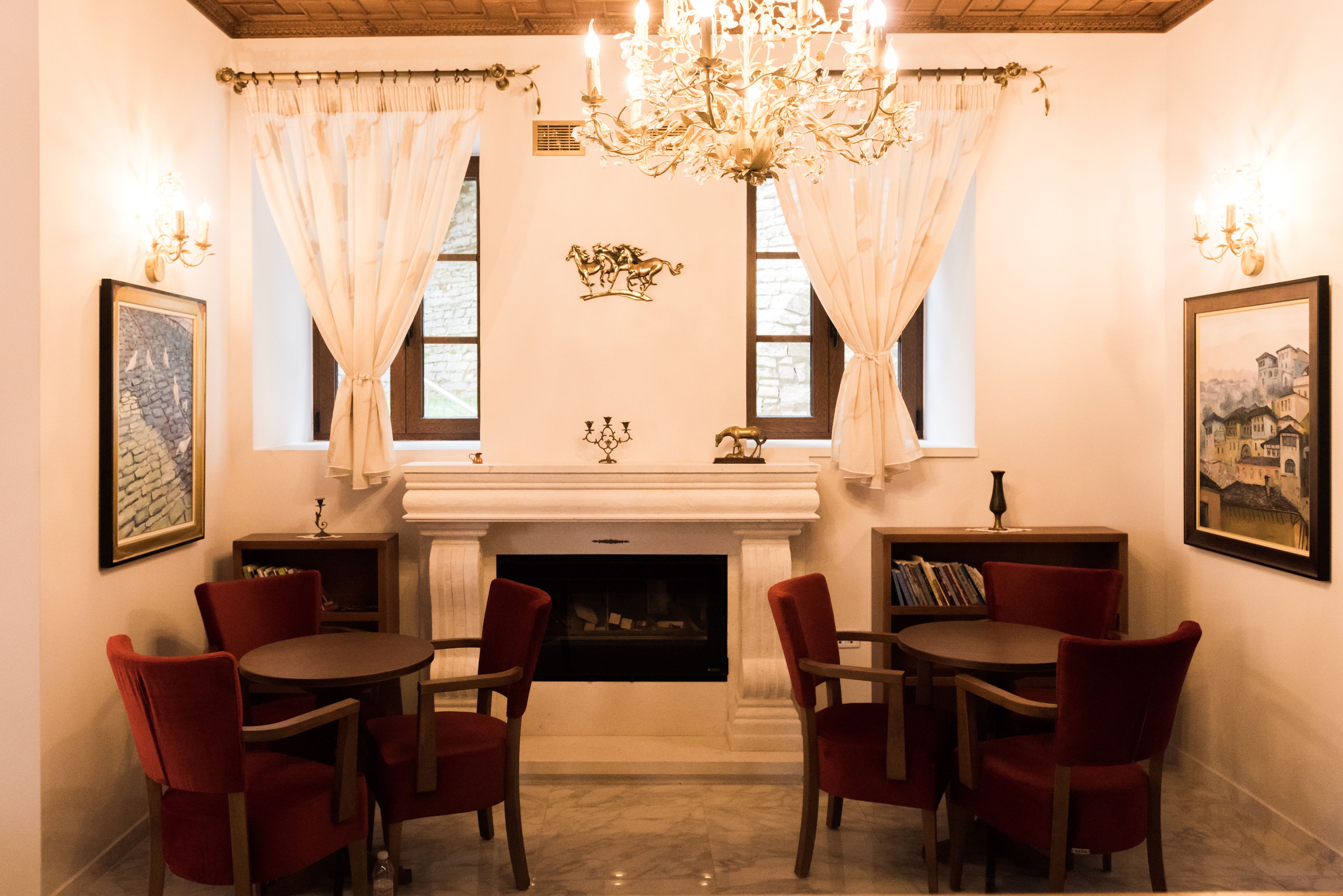 A dining area with a fireplace, red chairs, and a chandelier.