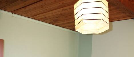 A bedroom with a wooden bed, a nightstand with a lamp, and a hanging light fixture.