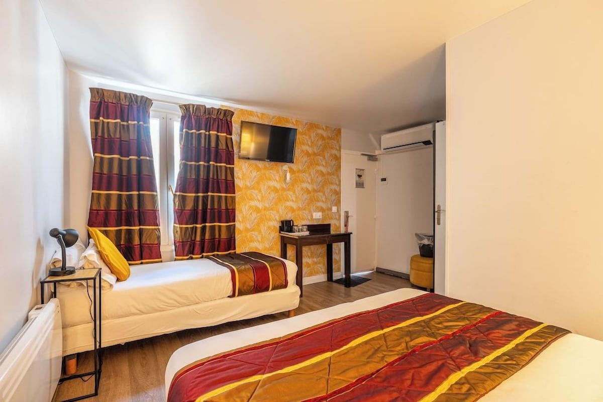 Une chambre d’hôtel avec deux lits, une télévision, un bureau et une armoire.