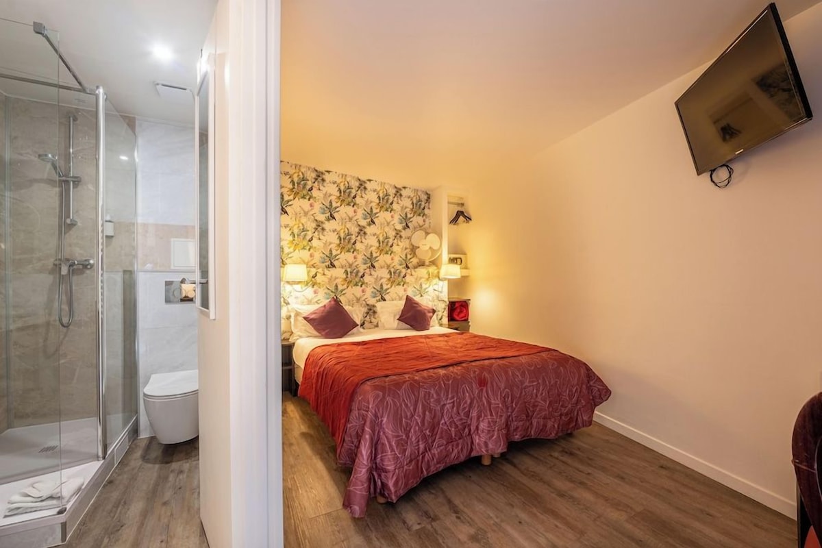 Une chambre avec un lit, une douche et un téléviseur fixé au mur.