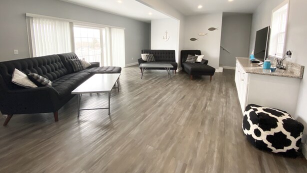 A modern living room with a sectional sofa, a small table, and a black armchair. - 140 S. Monroe St., Watkins Glen (Watkins Glen)