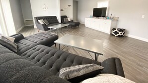 A modern living room with a sectional sofa, a coffee table, a TV, and a white cabinet. - 140 S. Monroe St., Watkins Glen (Watkins Glen)