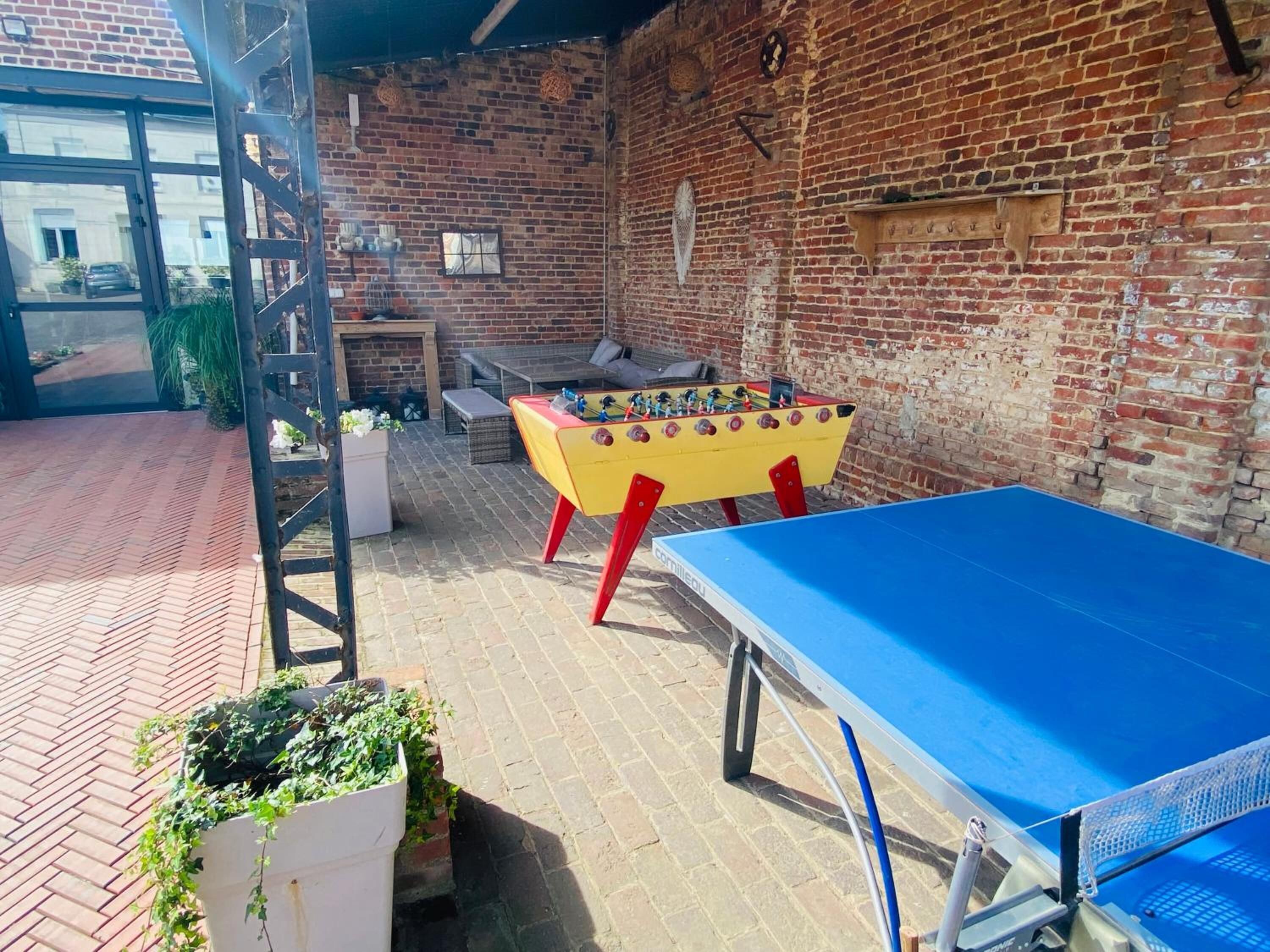 Un patio con mesa de fútbol de mesa, mesa de ping pong y pared de ladrillo.