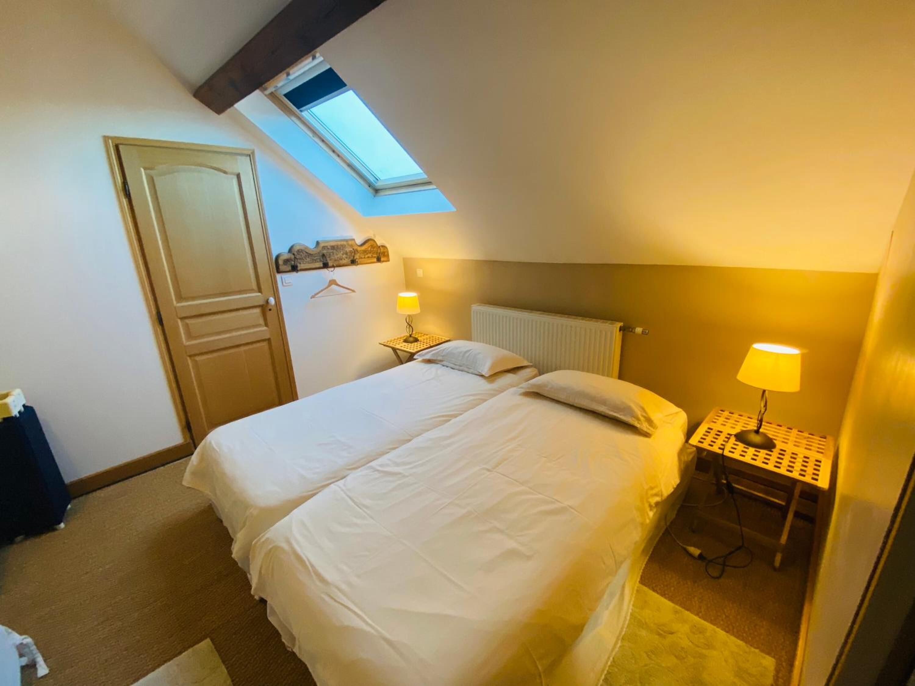 Une chambre avec un puits de lumière, un lit, une table de chevet avec une lampe et un radiateur.