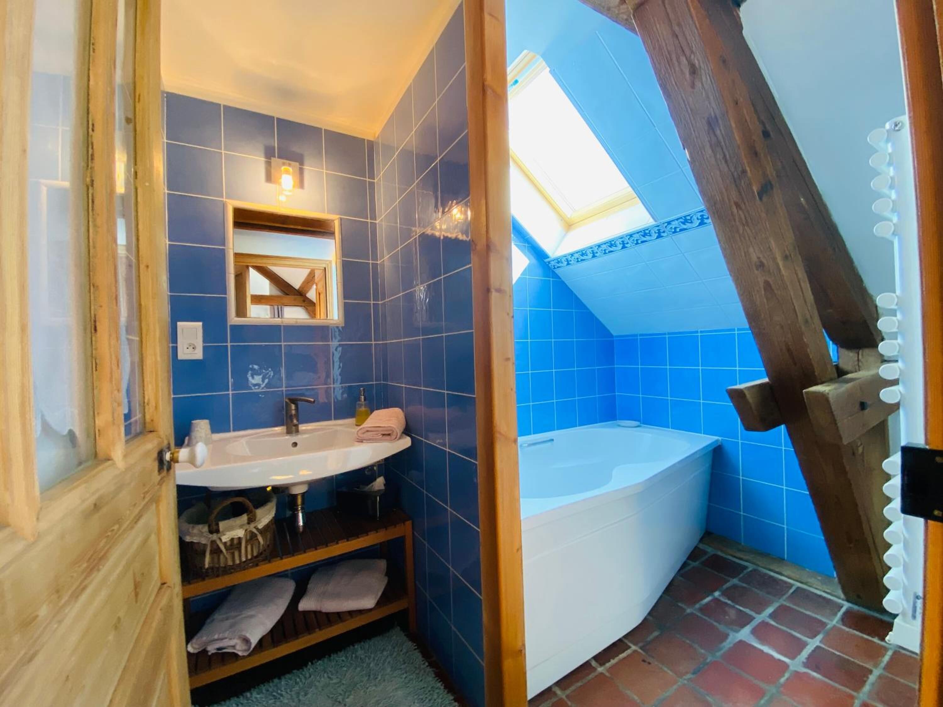 Une salle de bain avec un puits de lumière, une baignoire et un lavabo.