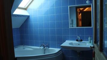 Un baño con azulejos azules, un tragaluz, una bañera y un lavabo.