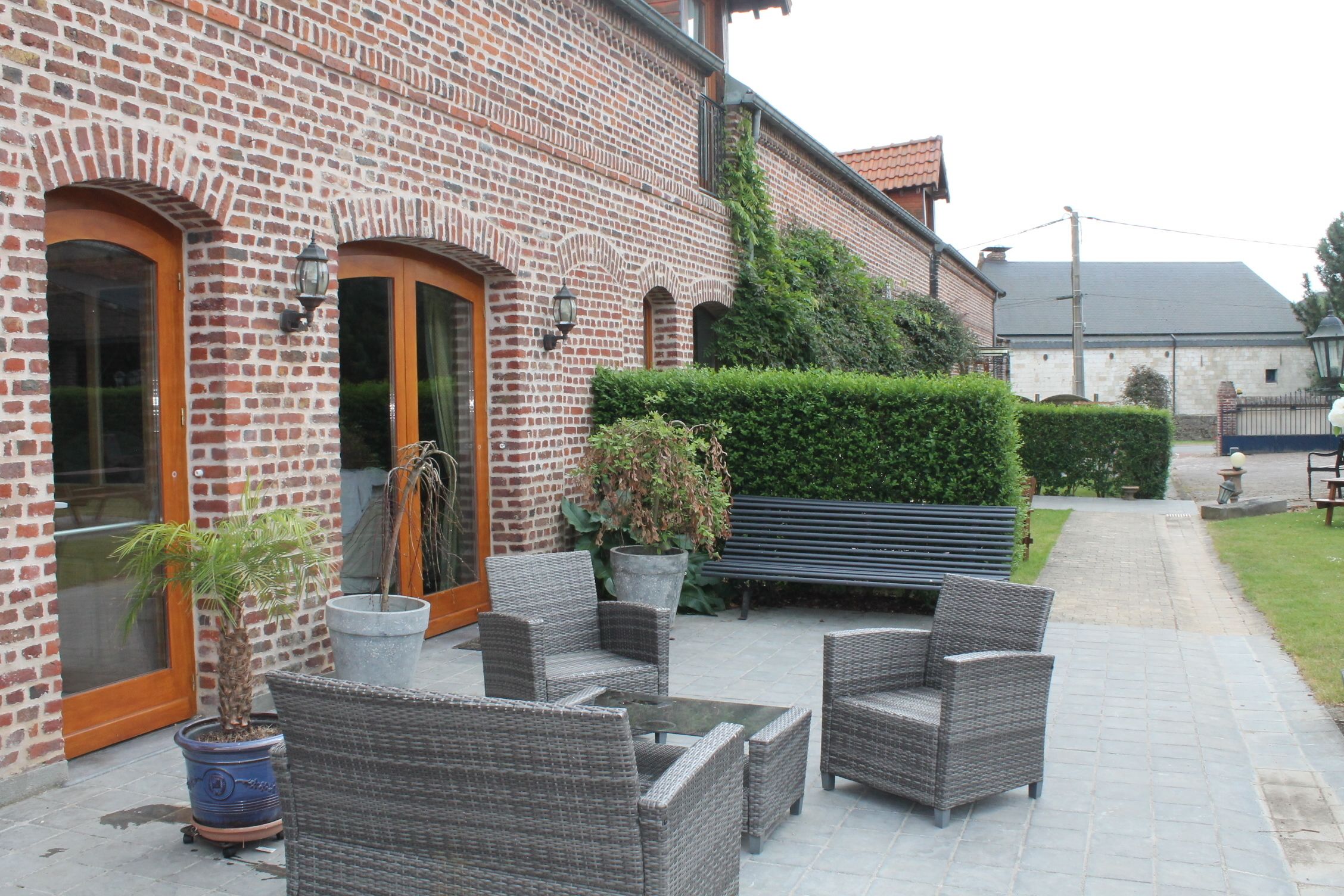 A brick building with a patio area featuring wicker furniture and potted plants.