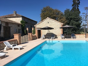 Una piscina al aire libre de temporada, sombrillas