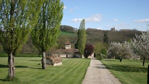 A rural landscape with a gravel path leading to a building surrounded by trees and a green field. - Le Farat (Auvillar)